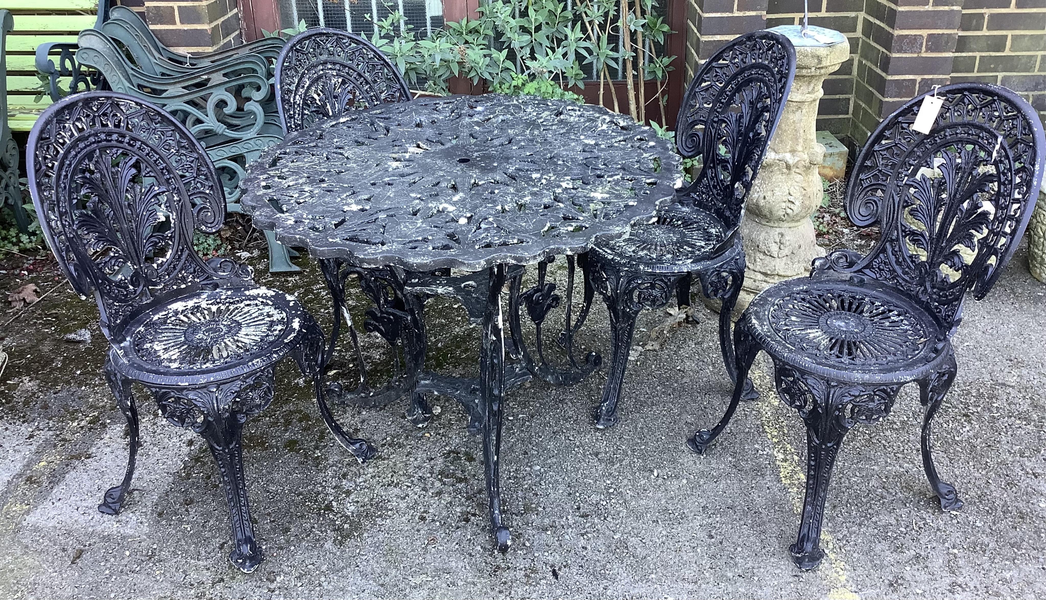 A Victorian style circular cast metal garden table, diameter 89cm, height 70cm together with four chairs. Condition - fair